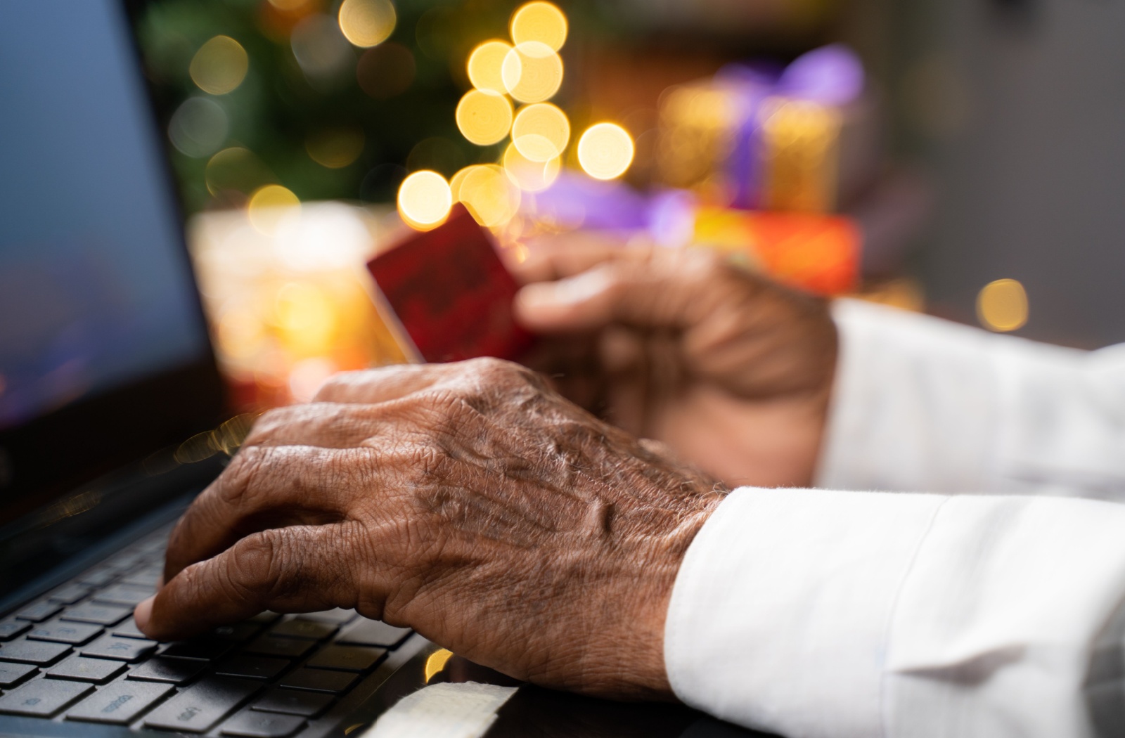 Close up of senior man’s hands holding credit card doing an online payment.