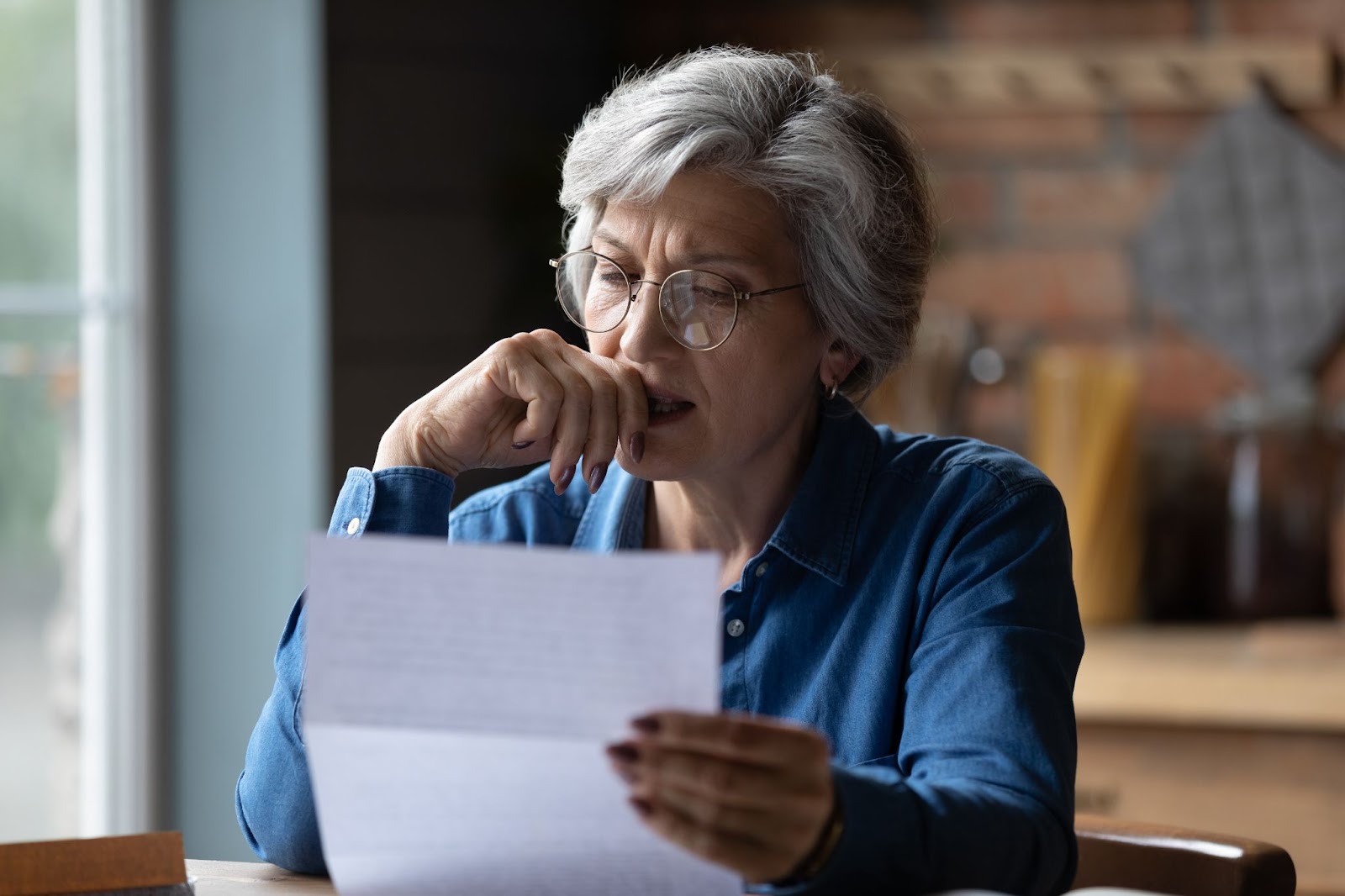 Distressed senior woman looking over financial reports.