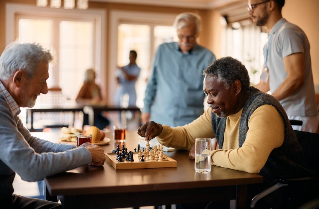 A group of friends in assisted living enjoy playing a game of chess.