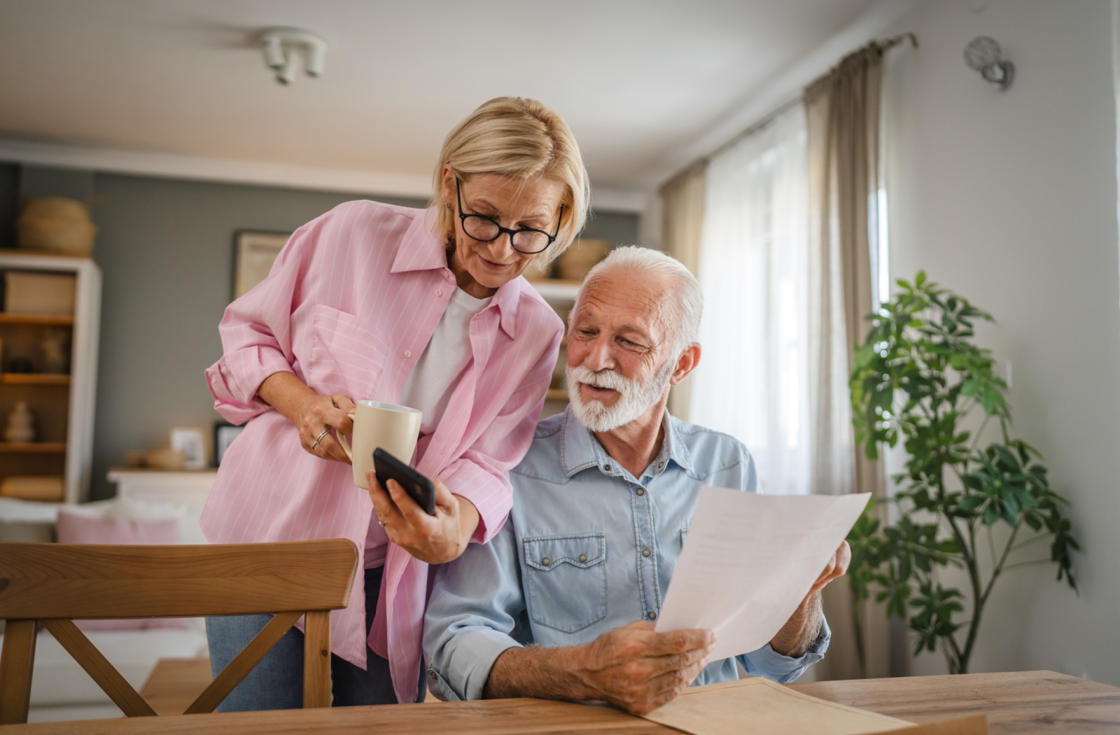 An older couple looking at alternatives on their phone and information sheets to assisted living.