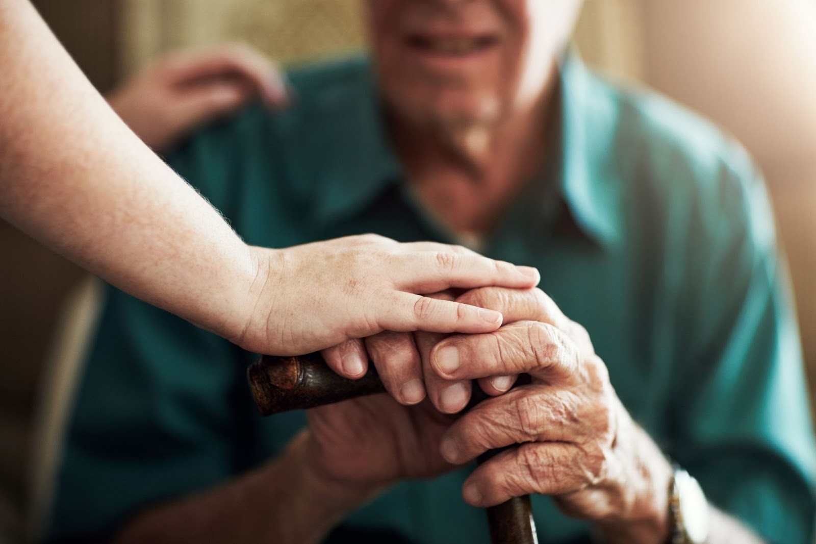 A hand holding another hand holding a cane to show support during the transition to senior living options.