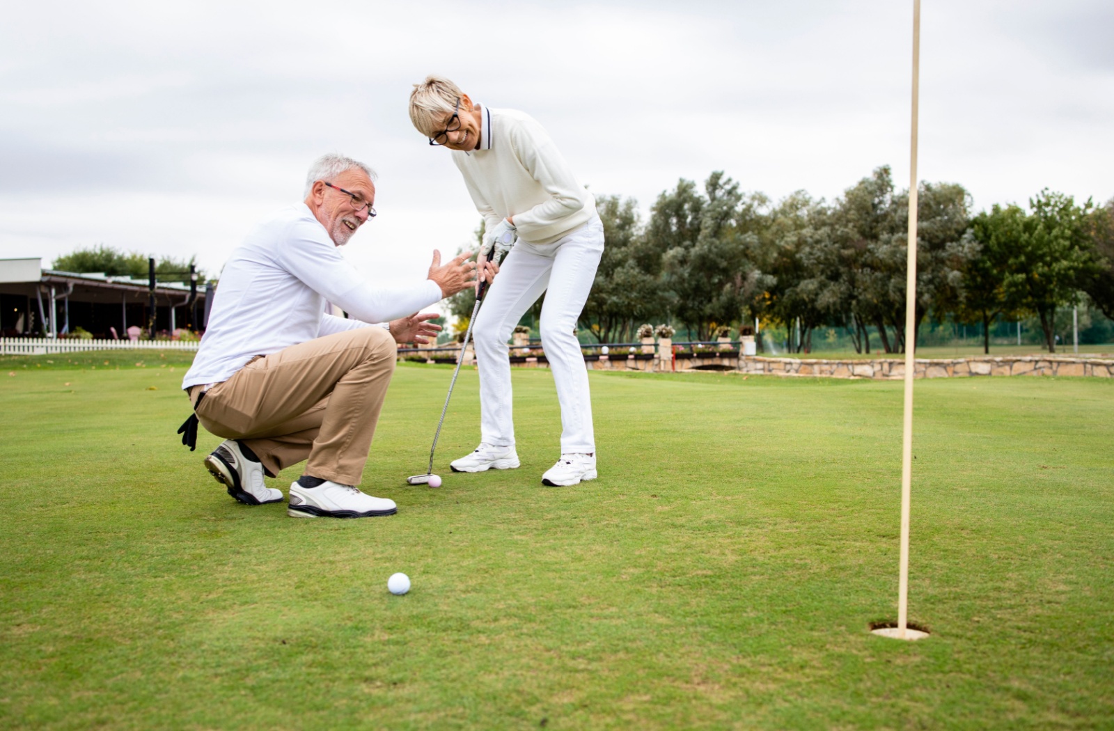 Older adult couple aiming to golf on a putting green.