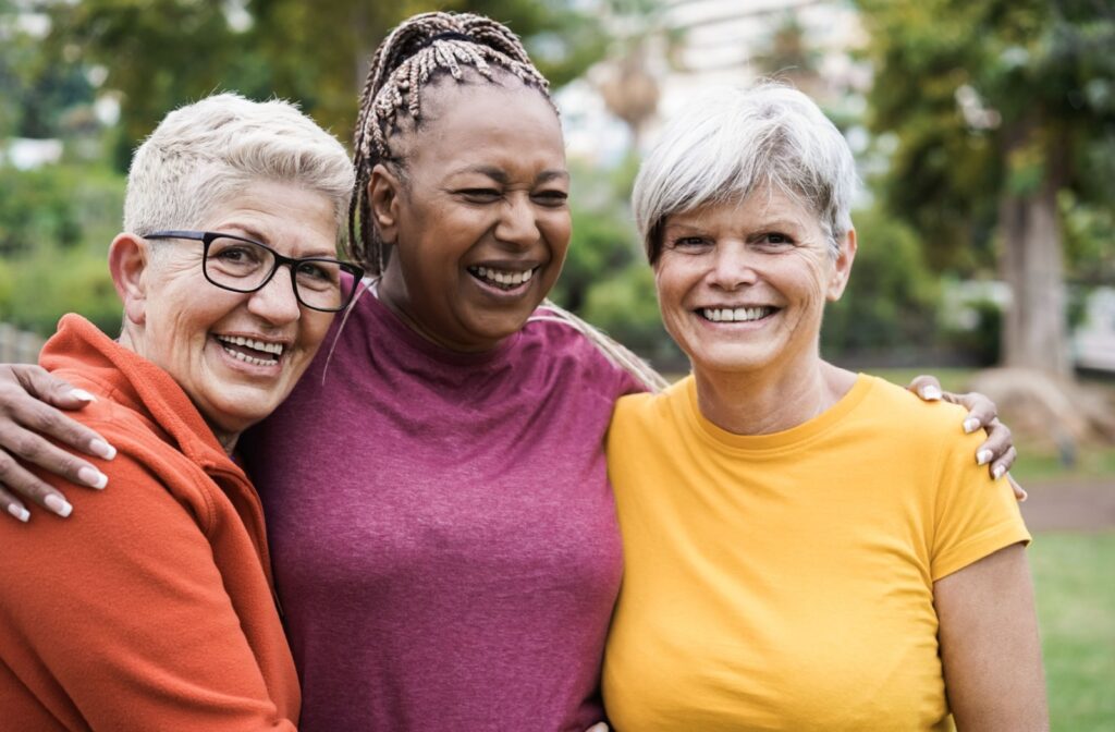 Three seniors share a hug while enjoying the outdoors and each other’s company and friendship