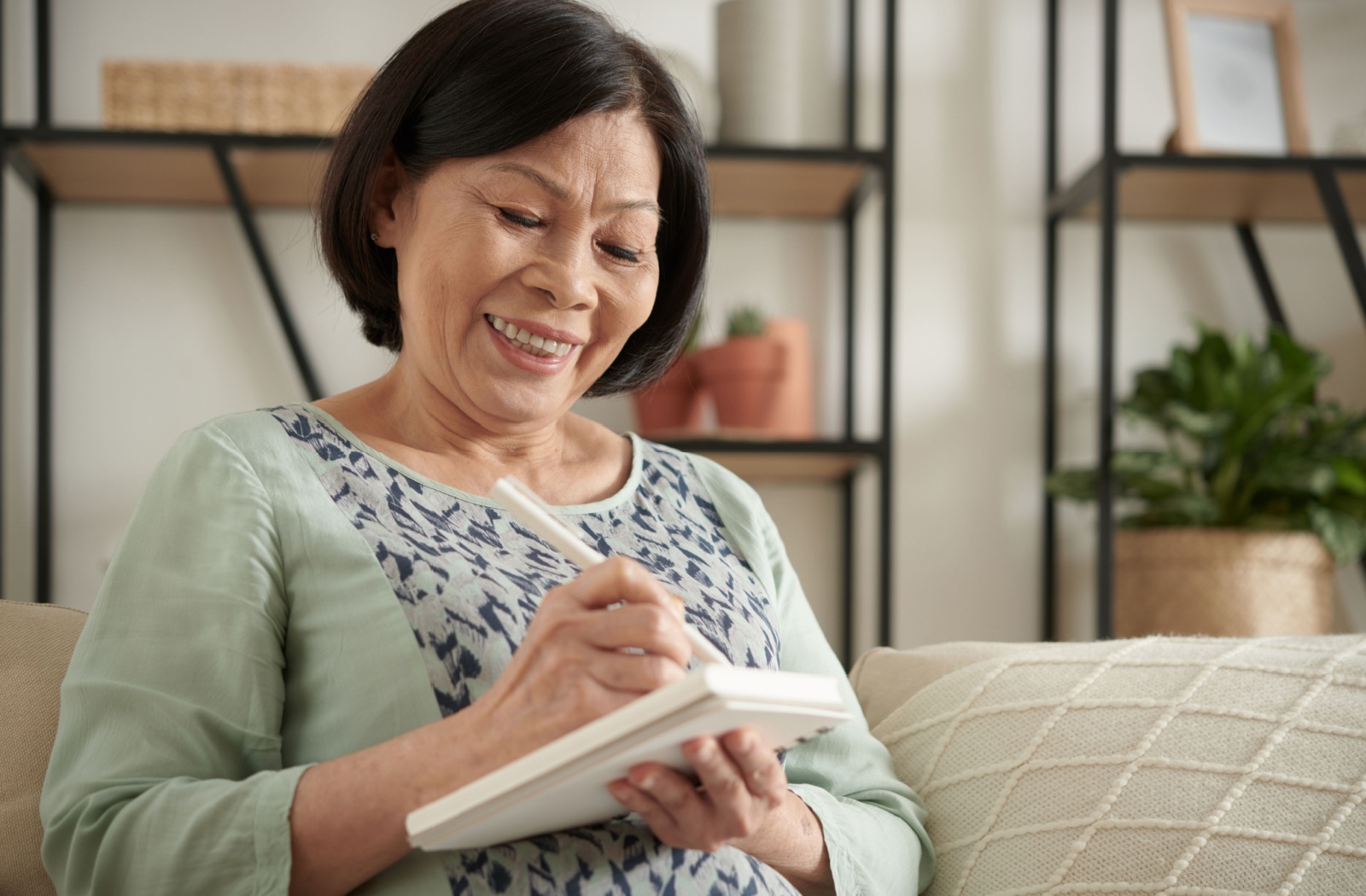 A senior smiles as they journal, thinking about the hobbies that brought them joy when they were younger